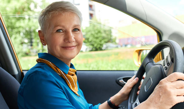 side-view-of-cheerful-middle-aged-woman-inside-car-on-driver-s-seat-with-hands-on-steering-wheel.jpeg